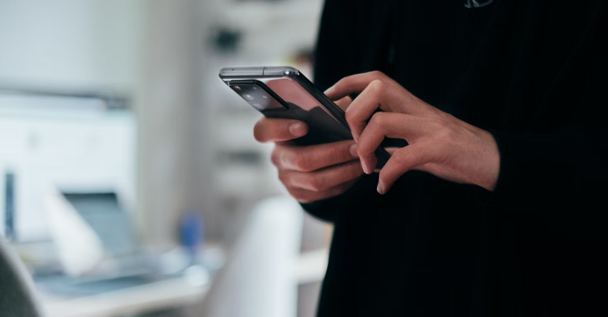 Person using smartphone in a modern workspace