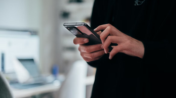 Person using smartphone in a modern workspace
