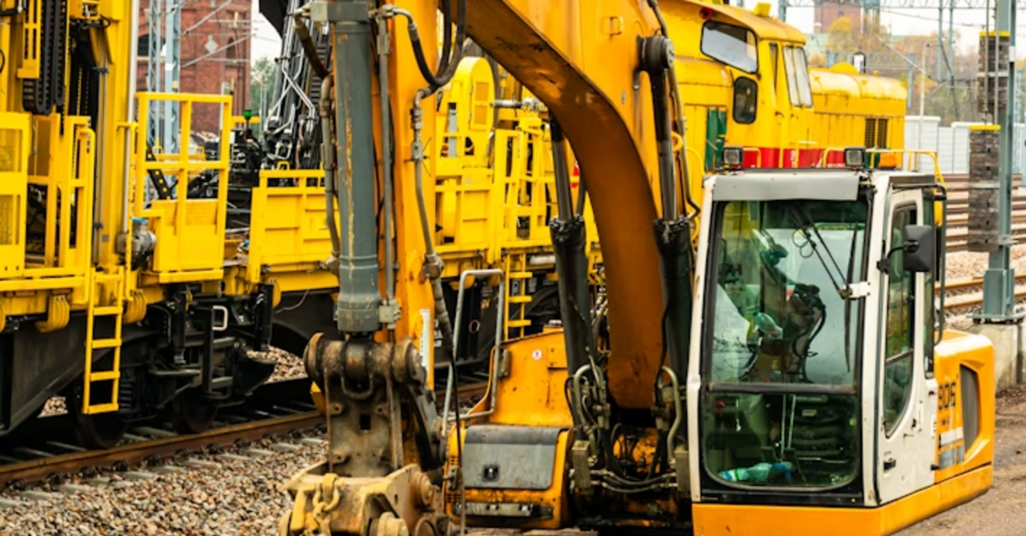 Yellow excavator and maintenance trains working on railway tracks
