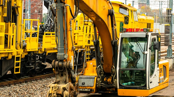 Yellow excavator and maintenance trains working on railway tracks