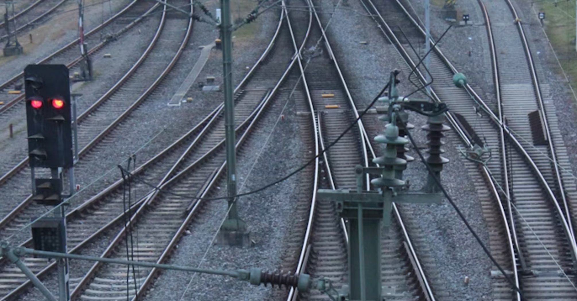 Multiple railway tracks with red signal and overhead wires