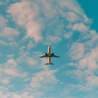 Airplane flying overhead against a partly cloudy sky