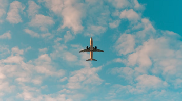 Airplane flying overhead against a partly cloudy sky