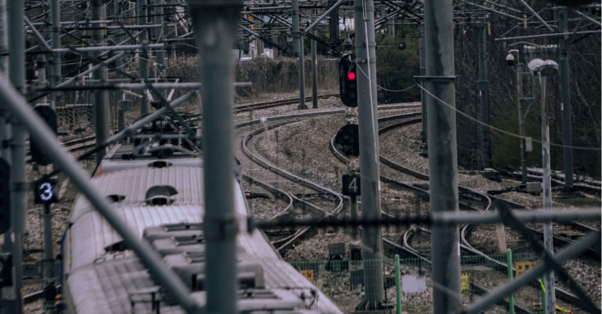 Train navigating complex rail junction under overhead infrastructure