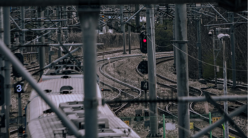 Train navigating complex rail junction under overhead infrastructure