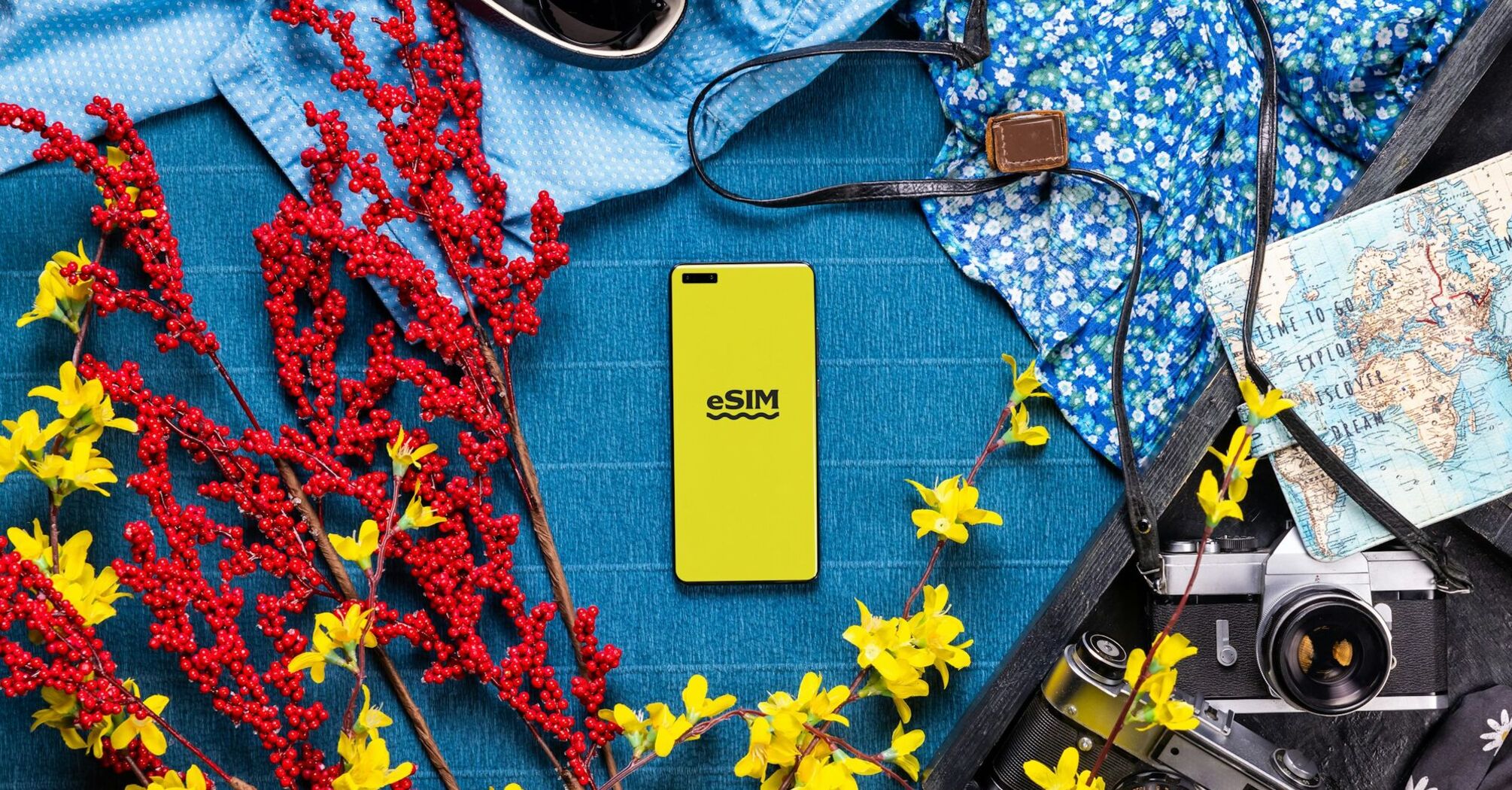 Smartphone with eSIM logo surrounded by travel essentials like flowers, map, camera, and sunglasses