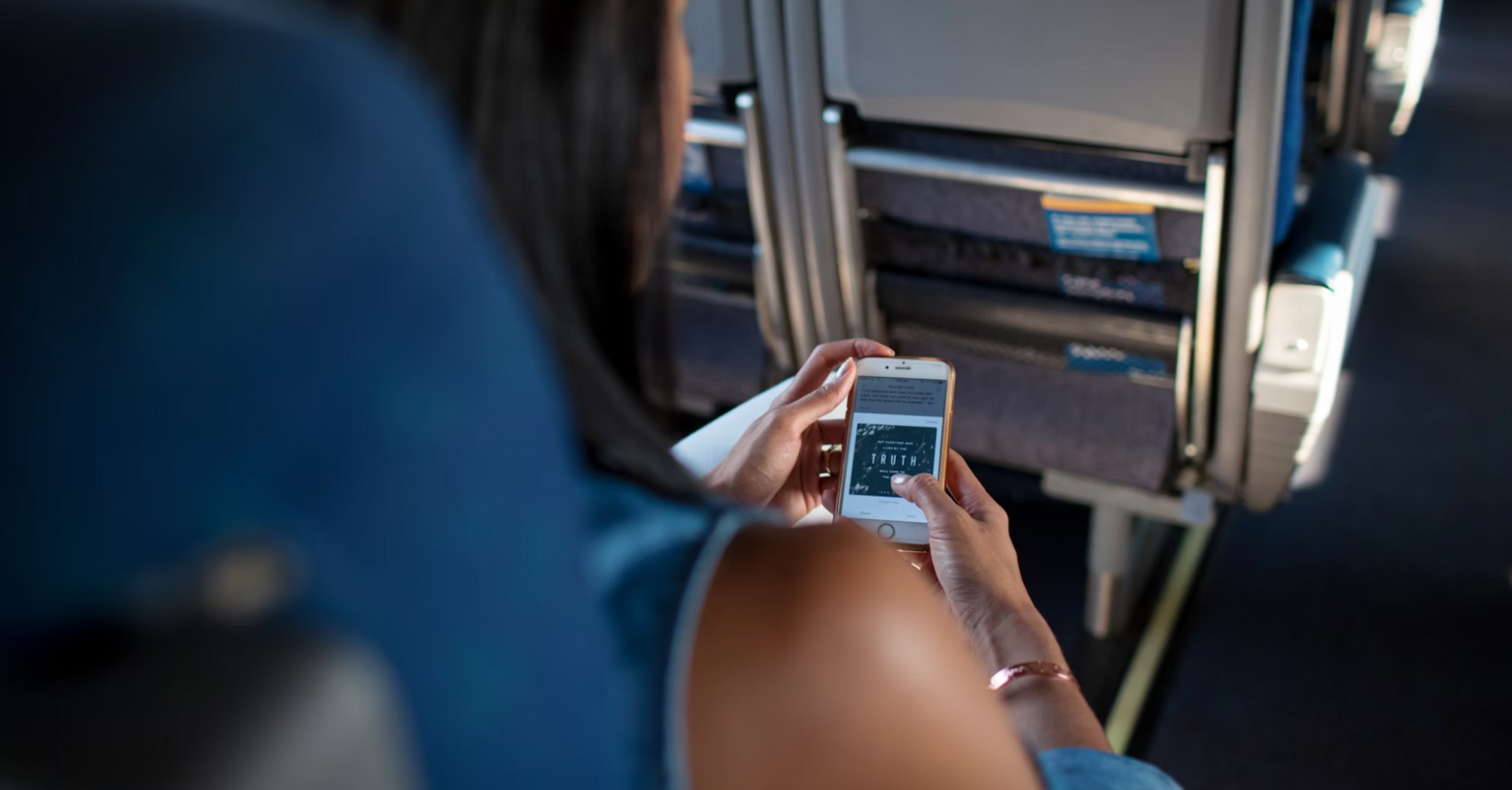 Woman checking travel information on her phone during a flight