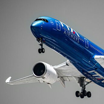 Blue ITA Airways aircraft taking off against grey sky