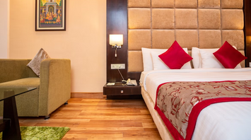 Modern hotel room with double bed, armchair, and wall art