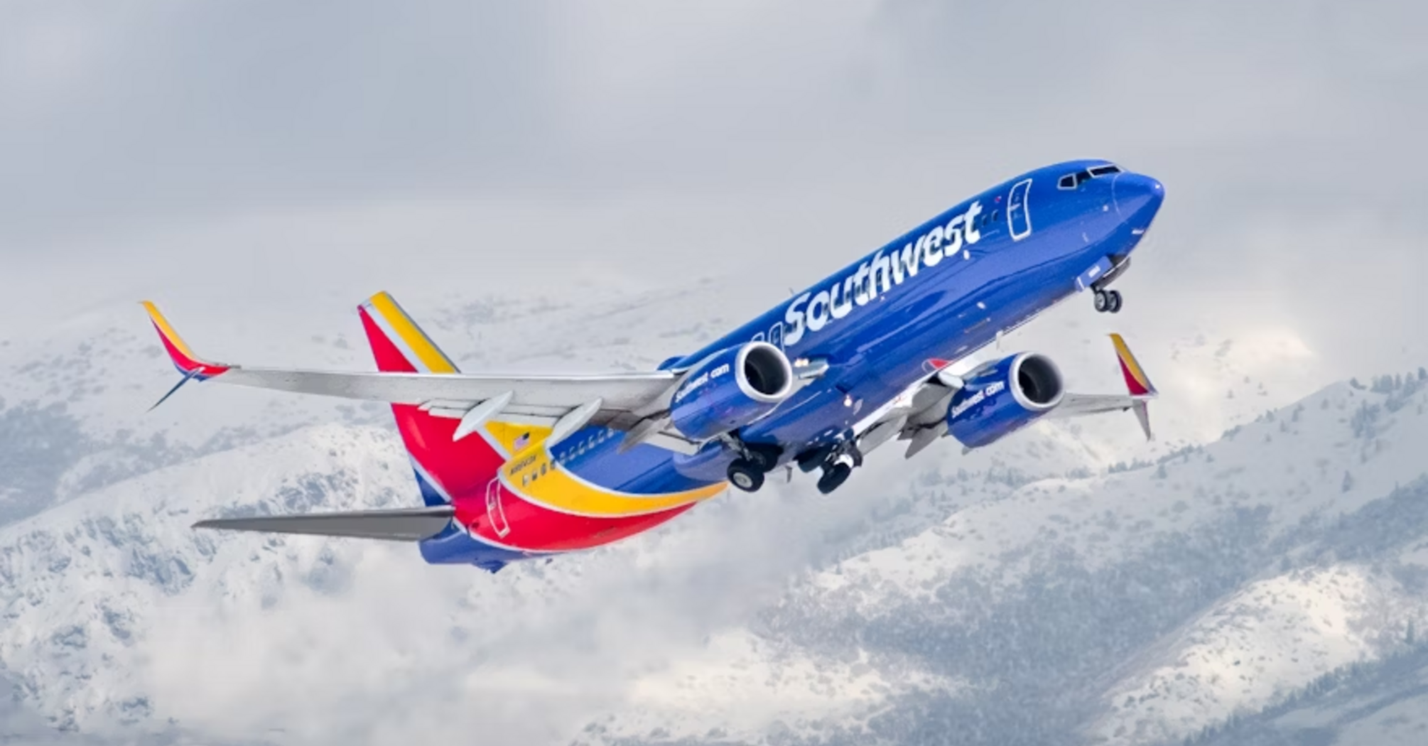 Southwest Airlines aircraft ascending with snowy mountains in the background