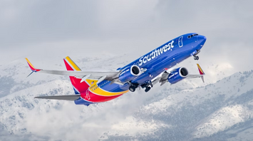 Southwest Airlines aircraft ascending with snowy mountains in the background