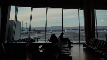 Passengers waiting at Oslo Gardermoen Airport gate with planes outside