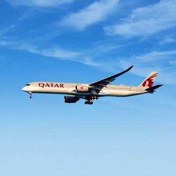 Qatar Airways aircraft in flight against blue sky