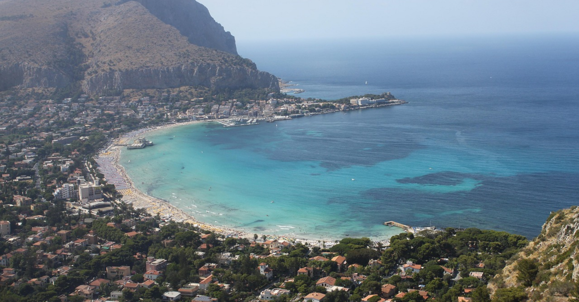 Aerial view of Mondello Beach in Palermo, Italy, with turquoise waters and a crowded shoreline