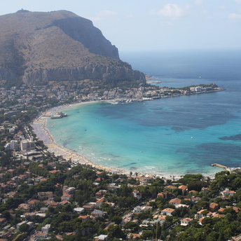 Aerial view of Mondello Beach in Palermo, Italy, with turquoise waters and a crowded shoreline