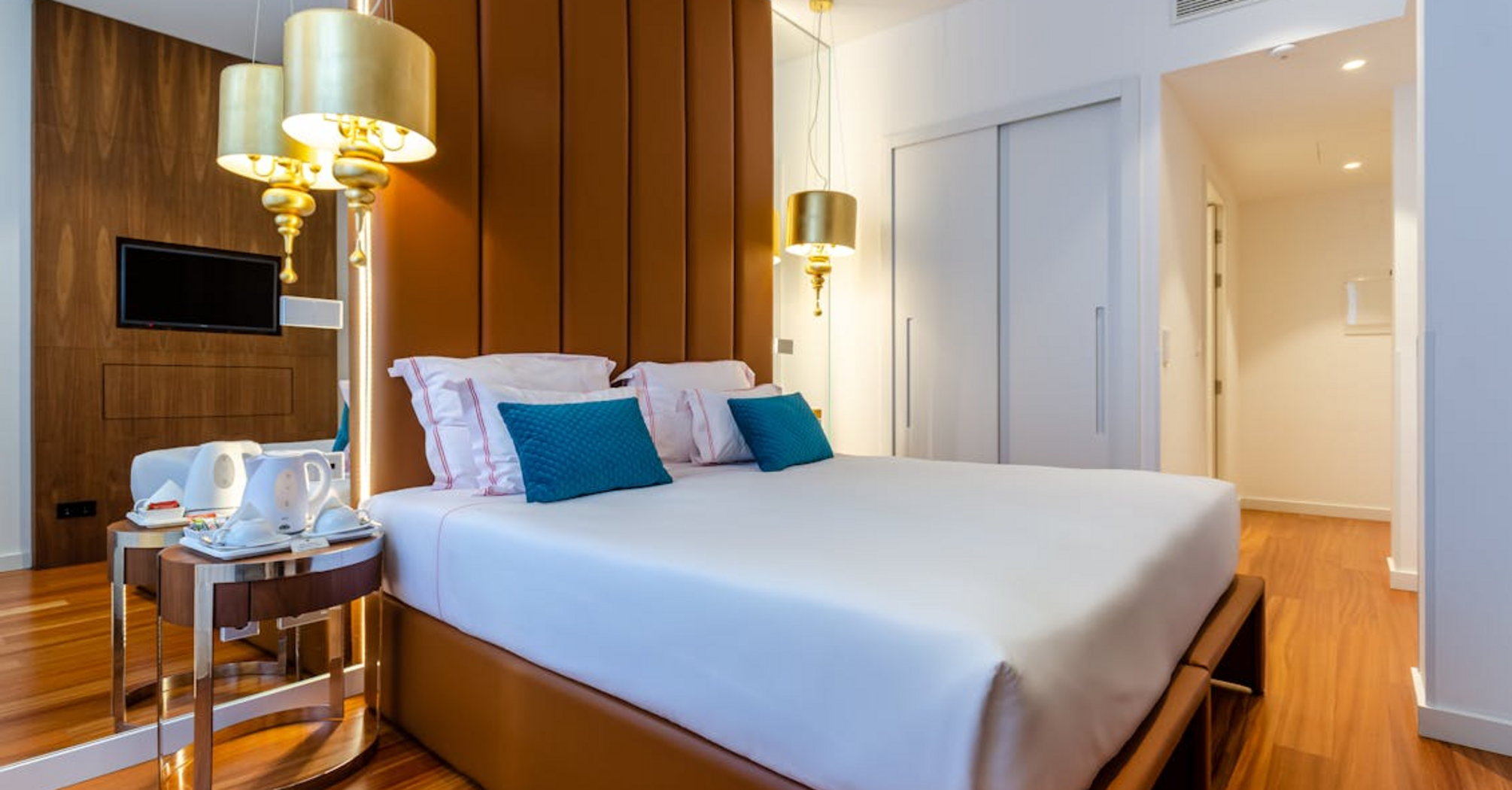 Modern hotel room with large bed, decorative pillows, and warm lighting