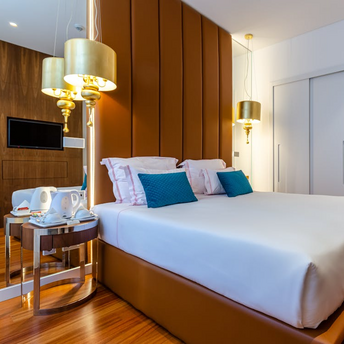 Modern hotel room with large bed, decorative pillows, and warm lighting