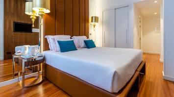 Modern hotel room with large bed, decorative pillows, and warm lighting