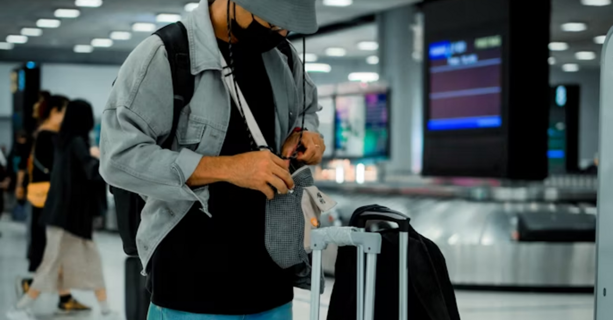Passenger checking carry-on luggage at airport baggage claim