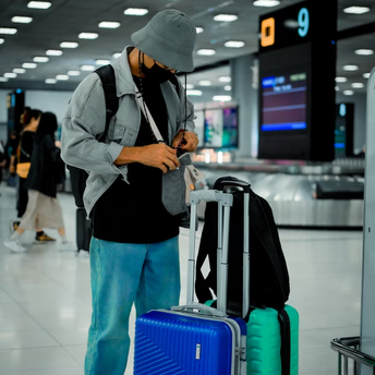 Passenger checking carry-on luggage at airport baggage claim