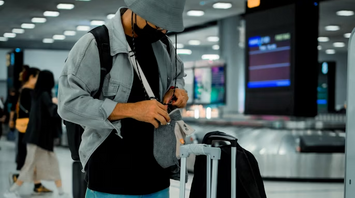 Passenger checking carry-on luggage at airport baggage claim
