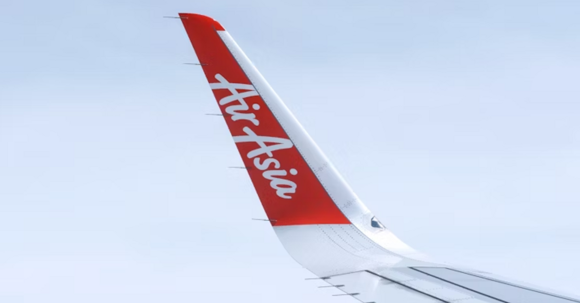 AirAsia airplane wing with logo against clear sky