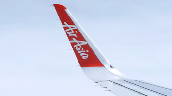 AirAsia airplane wing with logo against clear sky
