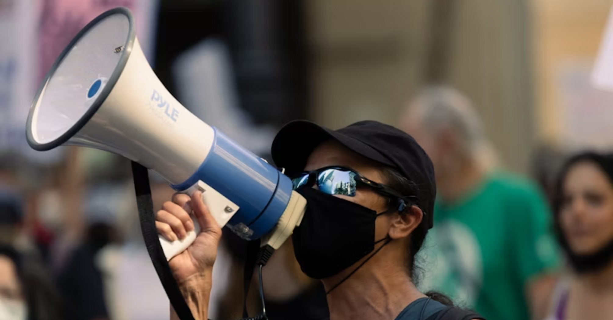 Person wearing mask using megaphone during a protest