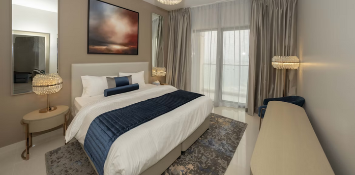 Modern hotel room with neutral tones, large bed, and floor-to-ceiling curtains