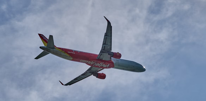 Vietnam Airlines plane flying against a partly cloudy sky