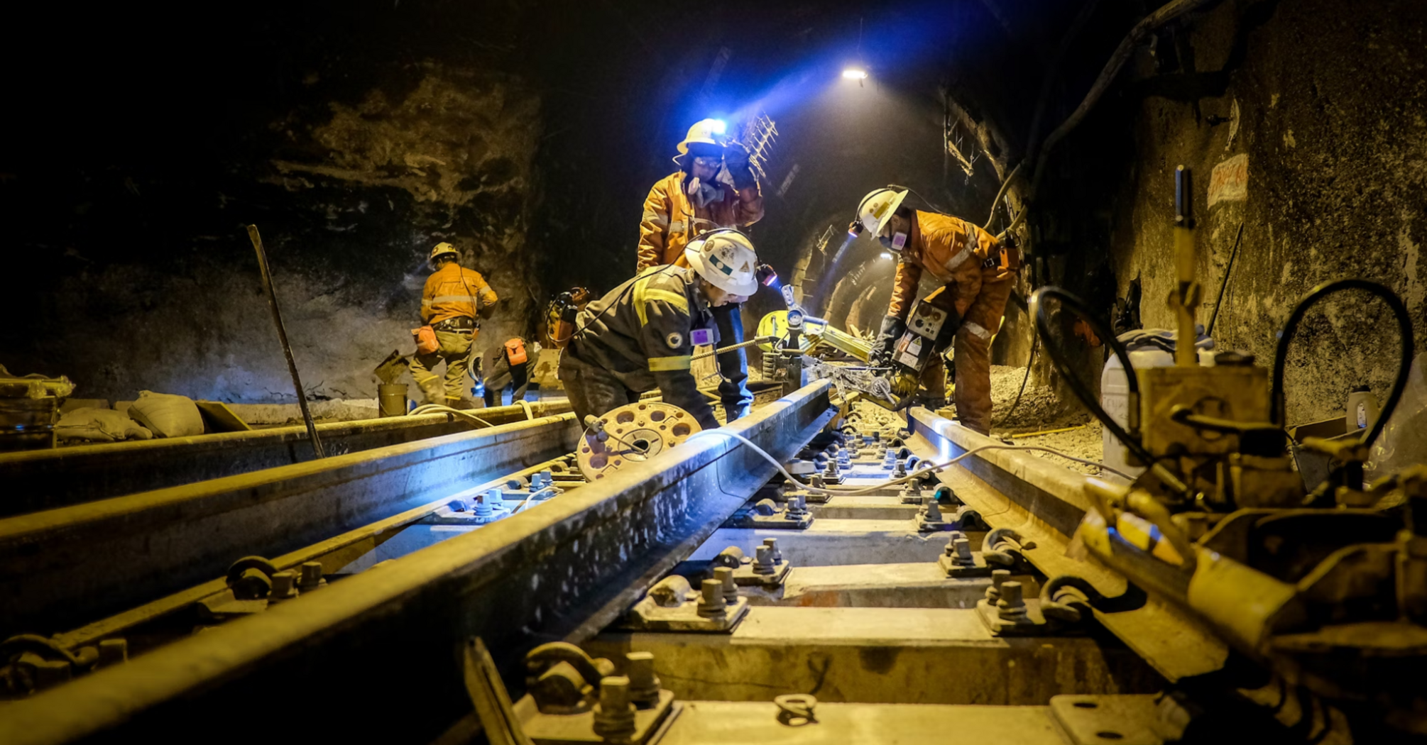 Rail workers conducting maintenance inside a tunnel at night