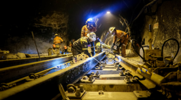 Rail workers conducting maintenance inside a tunnel at night