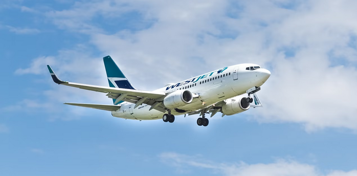 WestJet airplane landing with extended flaps against blue sky