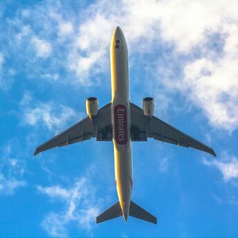 Emirates airplane flying against a blue sky