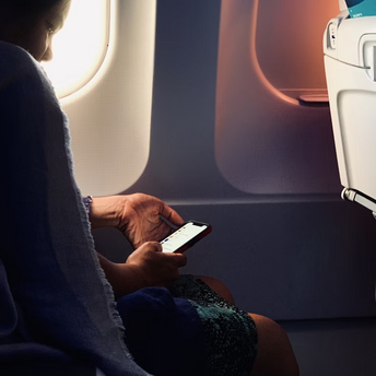 Passenger using smartphone on airplane with window light