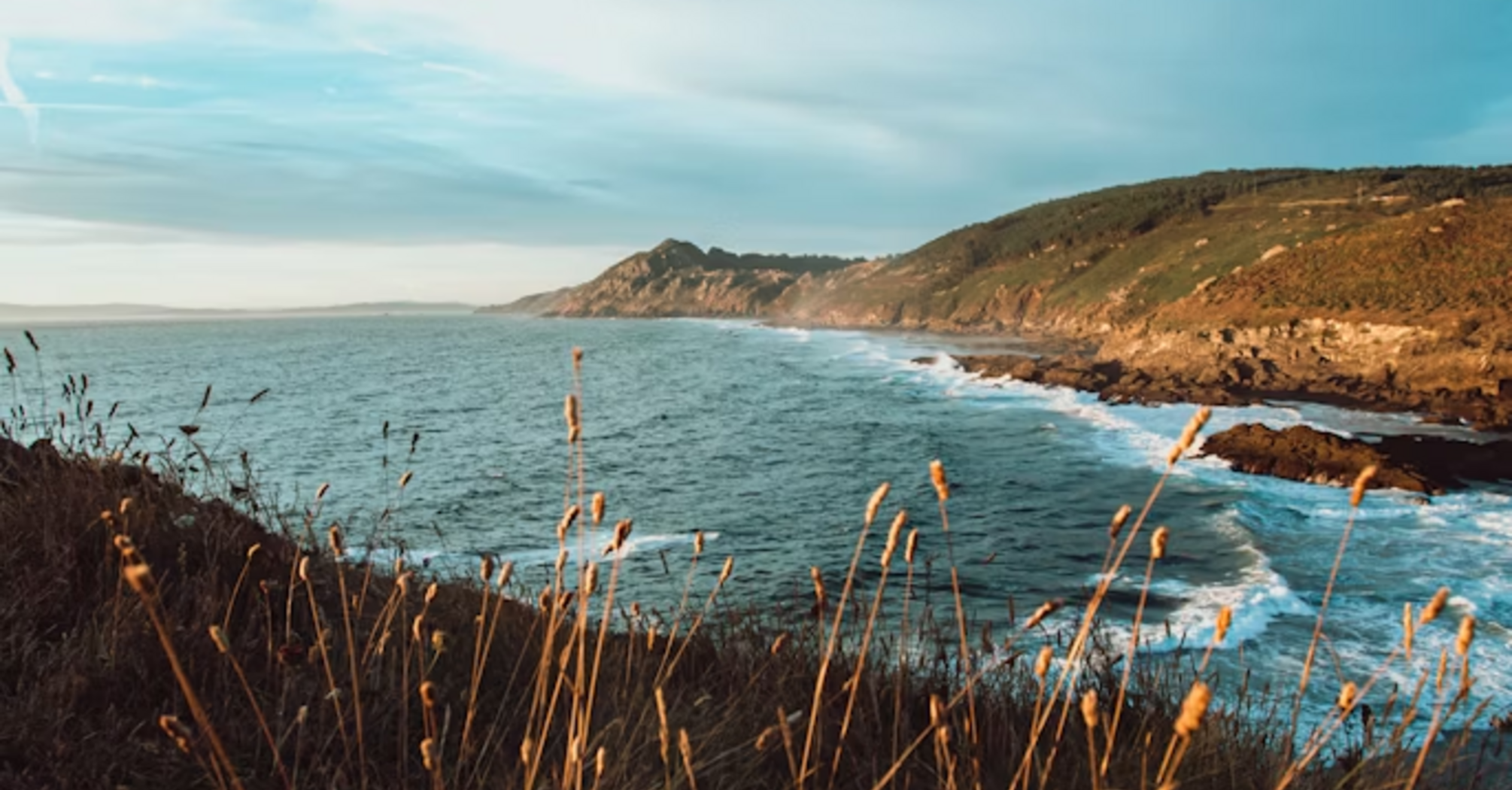 Coastal landscape with rugged cliffs and ocean waves under a clear sky