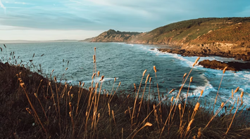 Coastal landscape with rugged cliffs and ocean waves under a clear sky