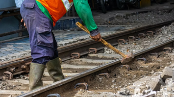 Construction worker carrying out maintenance on railway tracks with a sledgehammer