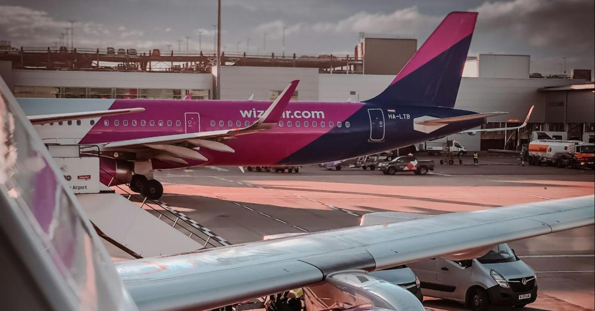 Wizz Air aircraft parked at airport gate with visible engine and tail branding