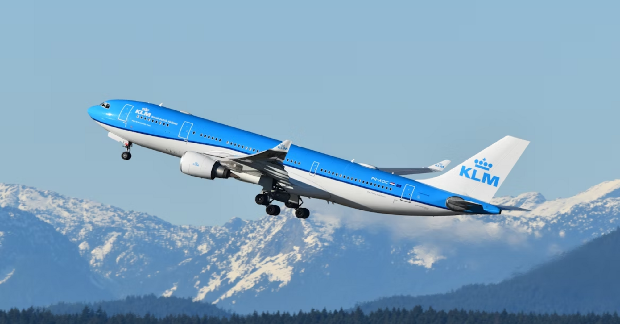 KLM aircraft taking off with snowy mountains in the background