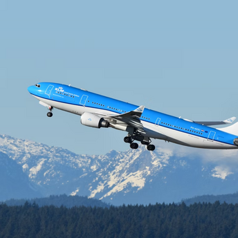KLM aircraft taking off with snowy mountains in the background