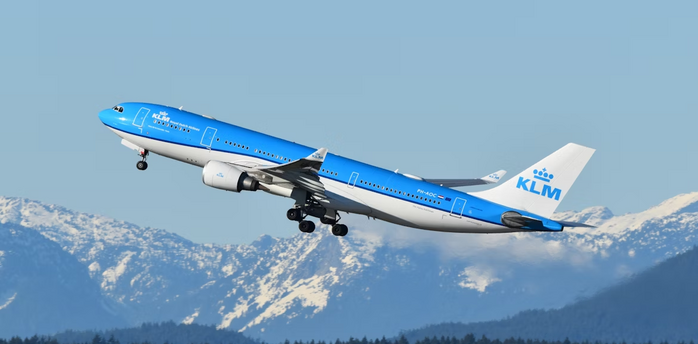 KLM aircraft taking off with snowy mountains in the background