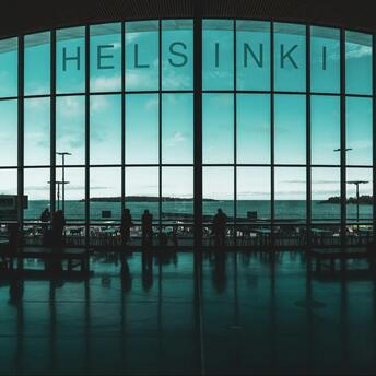 Silhouettes of travelers inside Helsinki Airport terminal with large window view