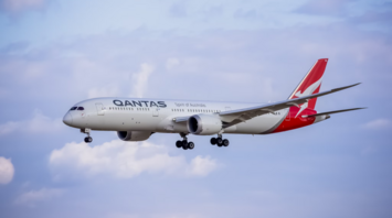 Qantas aircraft approaching for landing against blue sky