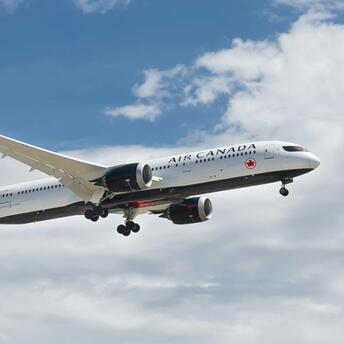 Air Canada airplane flying under cloudy sky