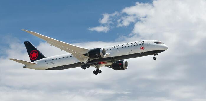 Air Canada airplane flying under cloudy sky