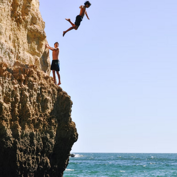 Two young men cliff diving into the sea