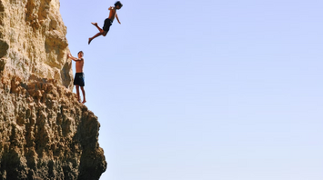 Two young men cliff diving into the sea