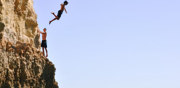 Two young men cliff diving into the sea