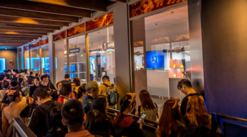 Passengers waiting in a crowded airport line near boarding gates